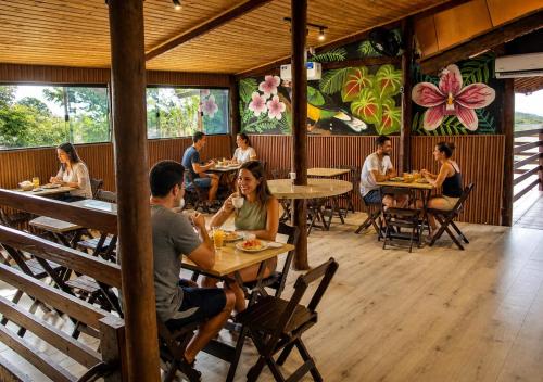 a group of people sitting at tables in a restaurant at Beija Flor Pousada in Ubatuba