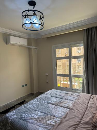 a bedroom with a bed and a chandelier and a window at Privado Modern Apartment Garden View B11 Group114 2BR in Madinaty