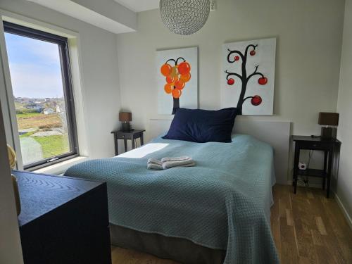 a bedroom with a bed with blue sheets and a window at Dugneberg in Karmøy