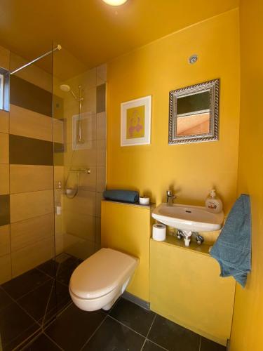 a yellow bathroom with a toilet and a sink at Guesthouse With Lake View in Veiðilundur