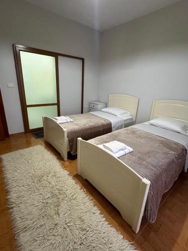 a bedroom with two beds and a rug at Camping & Guest House Herges in Udënisht