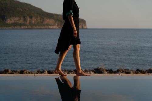 a woman walking on the beach near the water at Alkyon SeaSide Studios in Neo Itilo