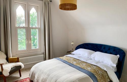 a bedroom with a bed with a blue headboard and a window at Norwood in Rushbrooke