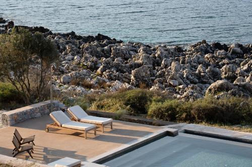 a patio with two chairs and a swimming pool at Alkyon SeaSide Studios in Neo Itilo