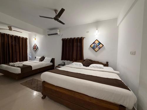 a bedroom with two beds and a ceiling fan at Aura Calangute in Calangute