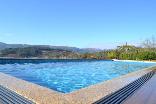 a swimming pool with blue water and mountains in the background at Encosta do Sossego in Cabeceiras de Basto