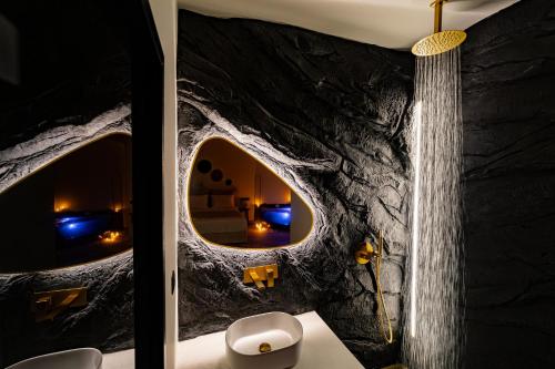 a room with a rock wall with a mirror at Andromeda Suite Private Jacuzzi & Cave Shower in Athens