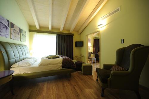a bedroom with a bed and a chair and a window at Parc Hotel Flora S in Riva del Garda