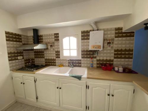 a white kitchen with a sink and a window at Djerba Sérénité in Houmt Souk