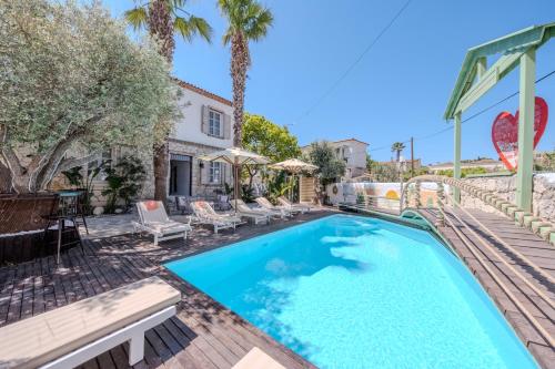 a pool with chairs and umbrellas next to a house at B House Alaçatı in Alaçatı