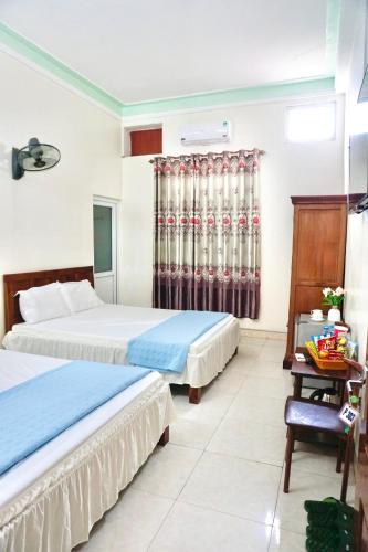 a hotel room with two beds and a desk at Nhà nghỉ Việt Mến in Sầm Sơn