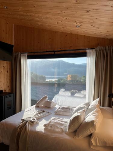 a bed in a room with a large window at Cabañas O Recuncho do Sor in O Barqueiro