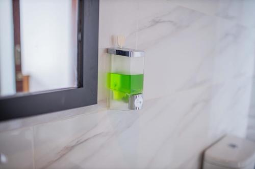 a bathroom with a green soap dispenser on the wall at Secret Point Huts in Nusa Lembongan