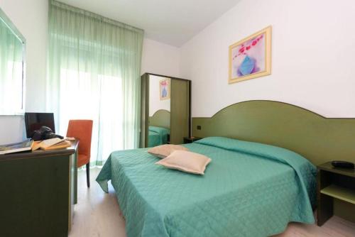 a bedroom with a green bed with a desk and a computer at Hotel Sirena in Lido di Camaiore