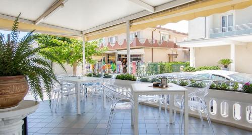 a patio with white tables and white chairs at Hotel Maria Luisa in Rimini