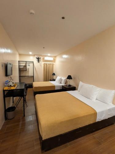 a hotel room with two beds and a desk at Top Star Hotel Manaoag in Manaoag