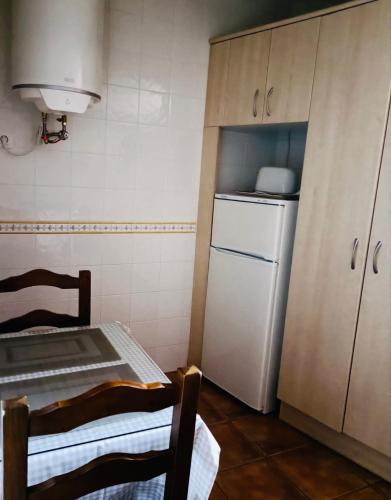 a small kitchen with a white refrigerator and a table at Parada del Carmen in Albarracín