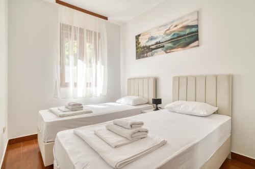 two beds in a white room with towels on them at Garni Hotel Milica in Herceg-Novi