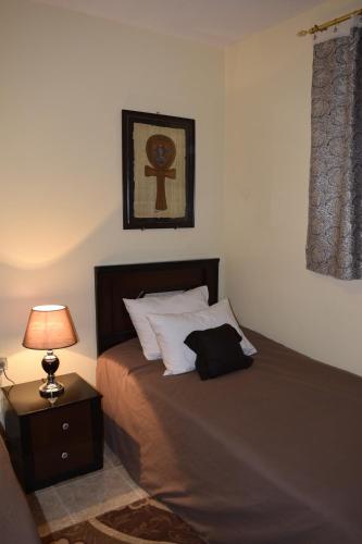 a bedroom with a bed with a lamp on a table at Pyramids Overlook Inn in Cairo