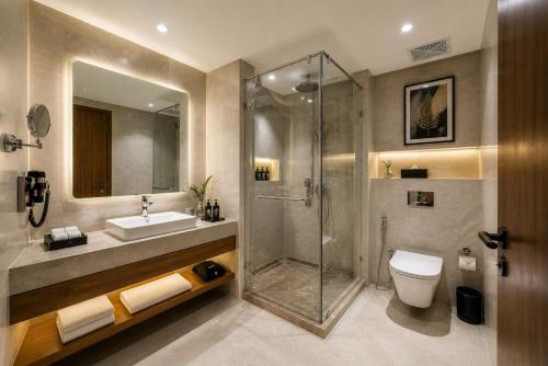 a bathroom with a shower and a toilet and a sink at Hotel Eden Suites Delhi Airport in New Delhi