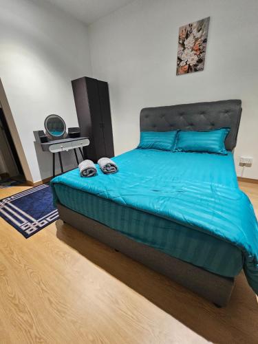 a bedroom with a bed with blue sheets and a table at Maru Maya Bay Guest House in Banting