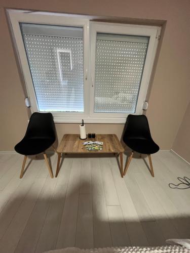a room with two chairs and a table and two windows at Apartmani Gala Foča in Foča