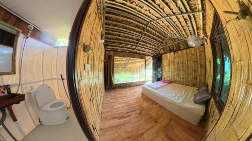 a small room with a bed and a toilet at Pu Luong Roots Homestay in Pu Luong