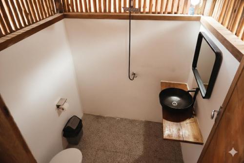 a small bathroom with a toilet and a tv at Buggei Surfcamp Mentawai in Katiet