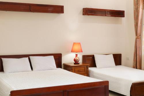 a bedroom with two beds and a lamp on a night stand at Khách sạn Nậm Rốm in Diện Biên Phủ