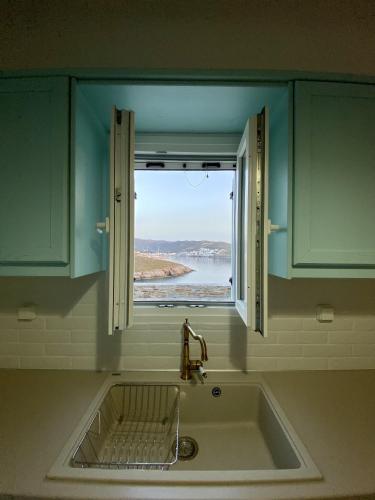 a sink in a kitchen with a window over it at Sto Faro - Blue in Kithnos