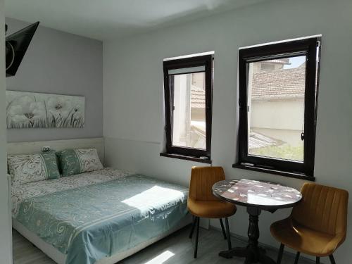 a bedroom with a bed and a table and two chairs at ВЛАД ДОМ Студио in Vratsa