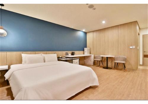 a bedroom with a large white bed and a blue wall at 엠플레이스호텔 in Incheon