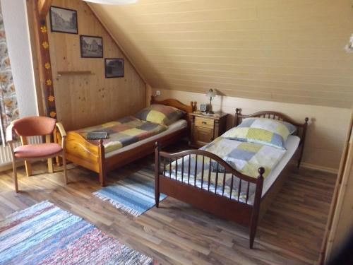 a bedroom with two beds and a chair at Gästehaus Hahnenkrug in Lottorf