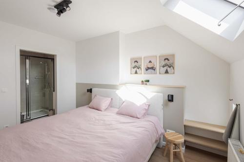 a bedroom with a white bed with pink pillows at Vakantiewoning Gast in Borgloon