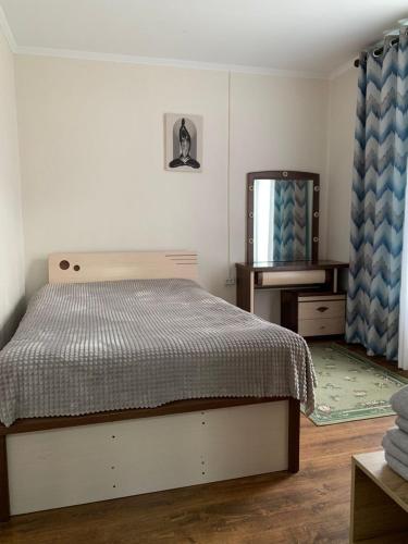 a bedroom with a bed and a dresser and a mirror at Rest House in Cholpon-Ata