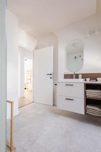 a white kitchen with a sink and a mirror at Vakantiewoning Gast in Borgloon