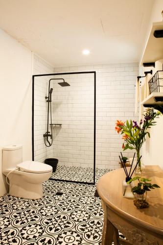 a bathroom with a shower with a toilet and a table at Balay Pahuwai Bed & Breakfast in Tagaytay
