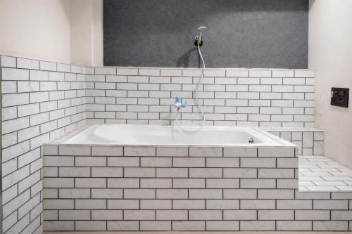 a white bath tub in a white tile bathroom at Hotel Bluesky in Surat