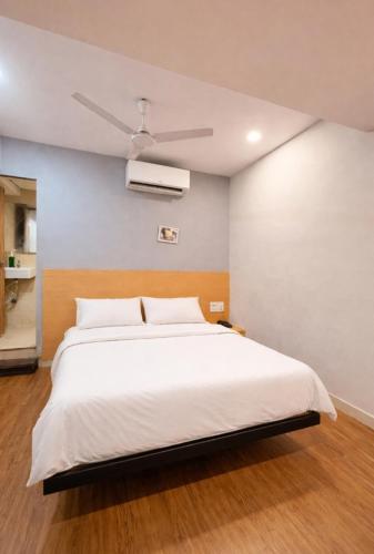 a bedroom with a white bed and a ceiling fan at Hotel Bluesky in Surat