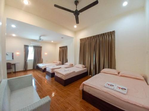 a bedroom with three beds and a ceiling fan at mulia homestay in Teluk Intan