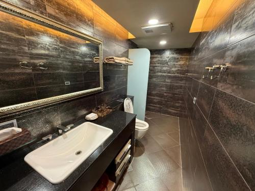 a bathroom with a sink and a toilet and a mirror at 木木 Lin in Chiayi City
