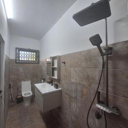 a bathroom with a white sink and a toilet at Oasis Mountain Retreat in Le Morne