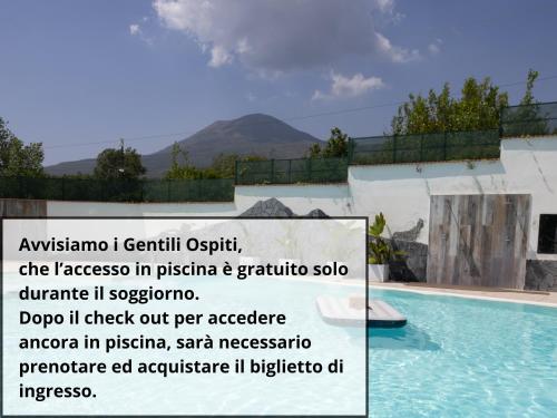 a sign next to a swimming pool with a mountain in the background at Vesuvio Inn Bed & Wine Experience in Boscotrecase