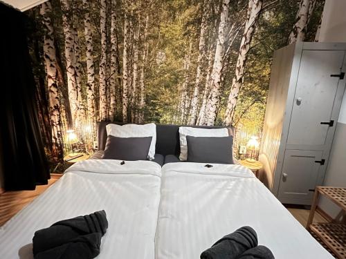 a bedroom with two beds with a mural of trees at B&B Itterhoeve in Neeritter