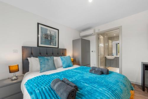 a bedroom with a large bed with a blue blanket at Duplex 2BR Flat with Parking Near Excellent Transport Links By Stay Aura Short Term Lets Brentford in Brentford