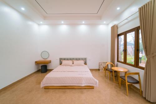 a bedroom with a bed and a table and chairs at Đồi Bông Village in Mục Uyên