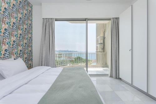 a bedroom with a bed and a large window at Bay B Blu,Modern 1BR Chalet -Seaview in Ed Dkârîne