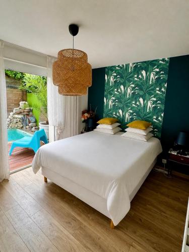 a bedroom with a large white bed with a green wall at Jasmin House in Cenon