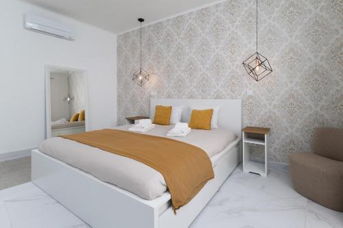 a white bedroom with a large bed and a chair at Villa Aurora in Livramento