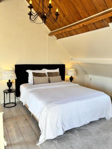 a bedroom with a large white bed with a wooden ceiling at Maison Blakenburg in Wissenkerke